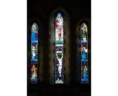The three stained glass windows together that make up the East window, designed by the Pre-Raphaelite artist Edward Burne-Jones, at St James Church, Staveley, Cumbria.