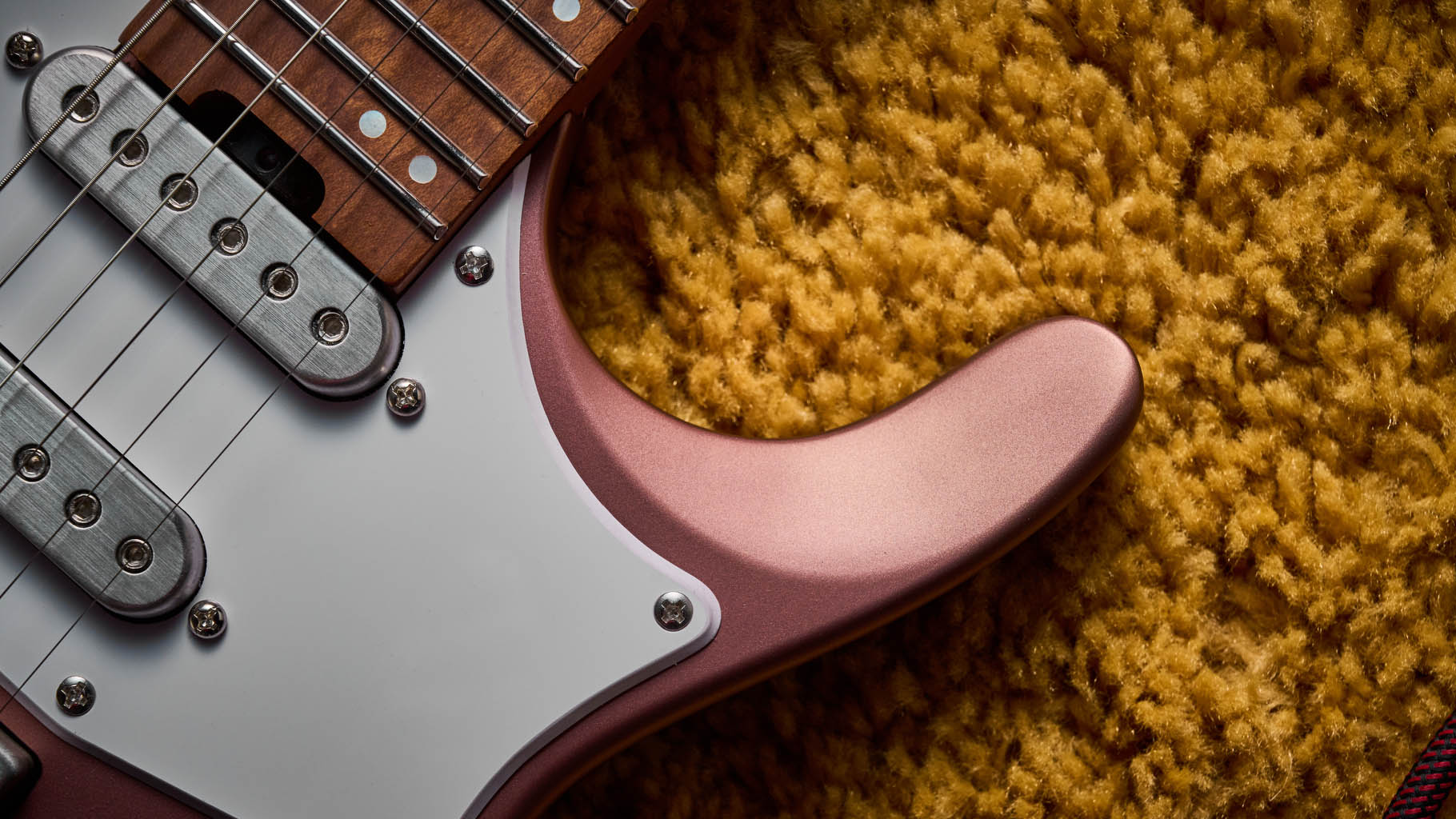 Ibanez Q54W: the headless electric guitar is finished in Copper Metallic Matte and photographed against a thick light-tan colored carpet.