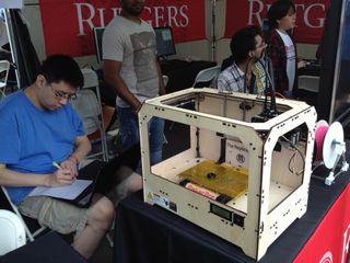 A 3D printer creates a black, plastic ring at World Maker Faire New York on Sept. 21, 2013.
