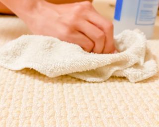 Close up of hand blotting a cream low-pile carpet with a cream cloth