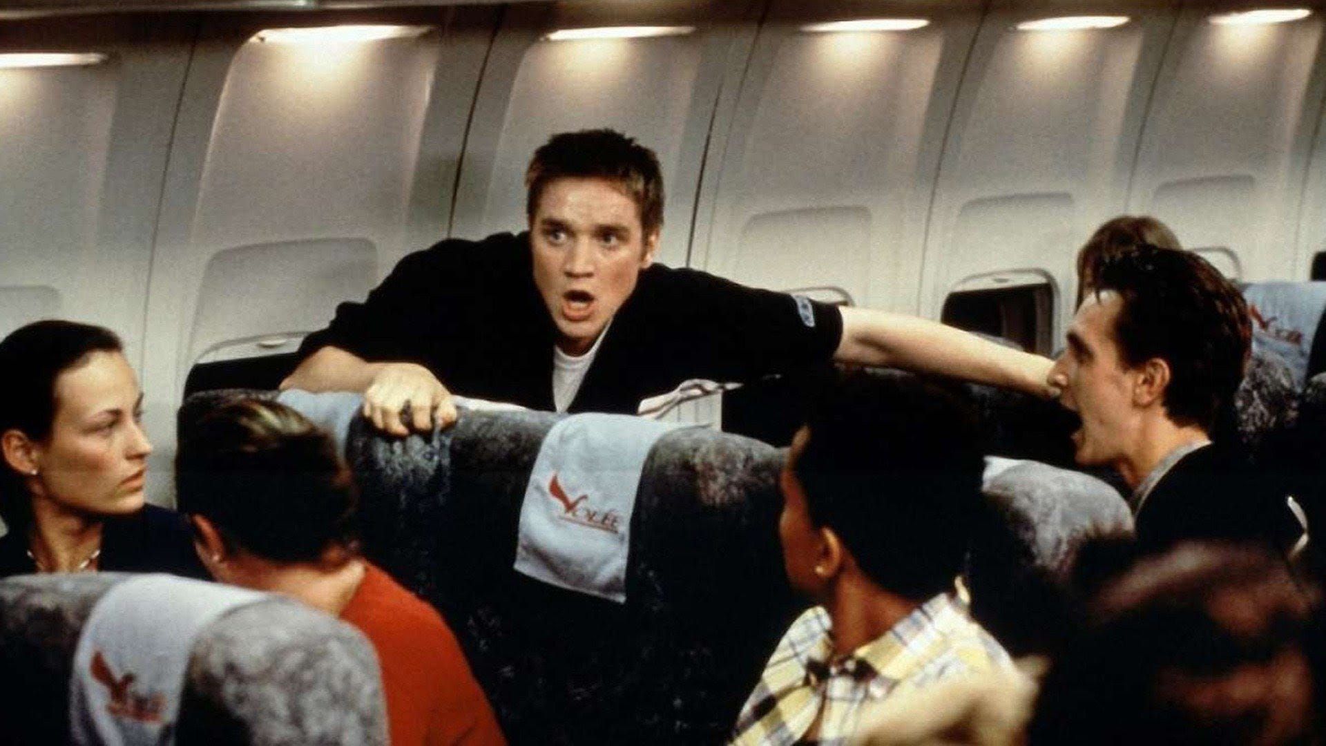 A man grabs plane seats around him in fear as other passengers watch in concern