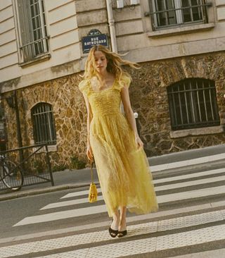 seorang model mengenakan gaun midi berwarna kuning dengan korset ruched