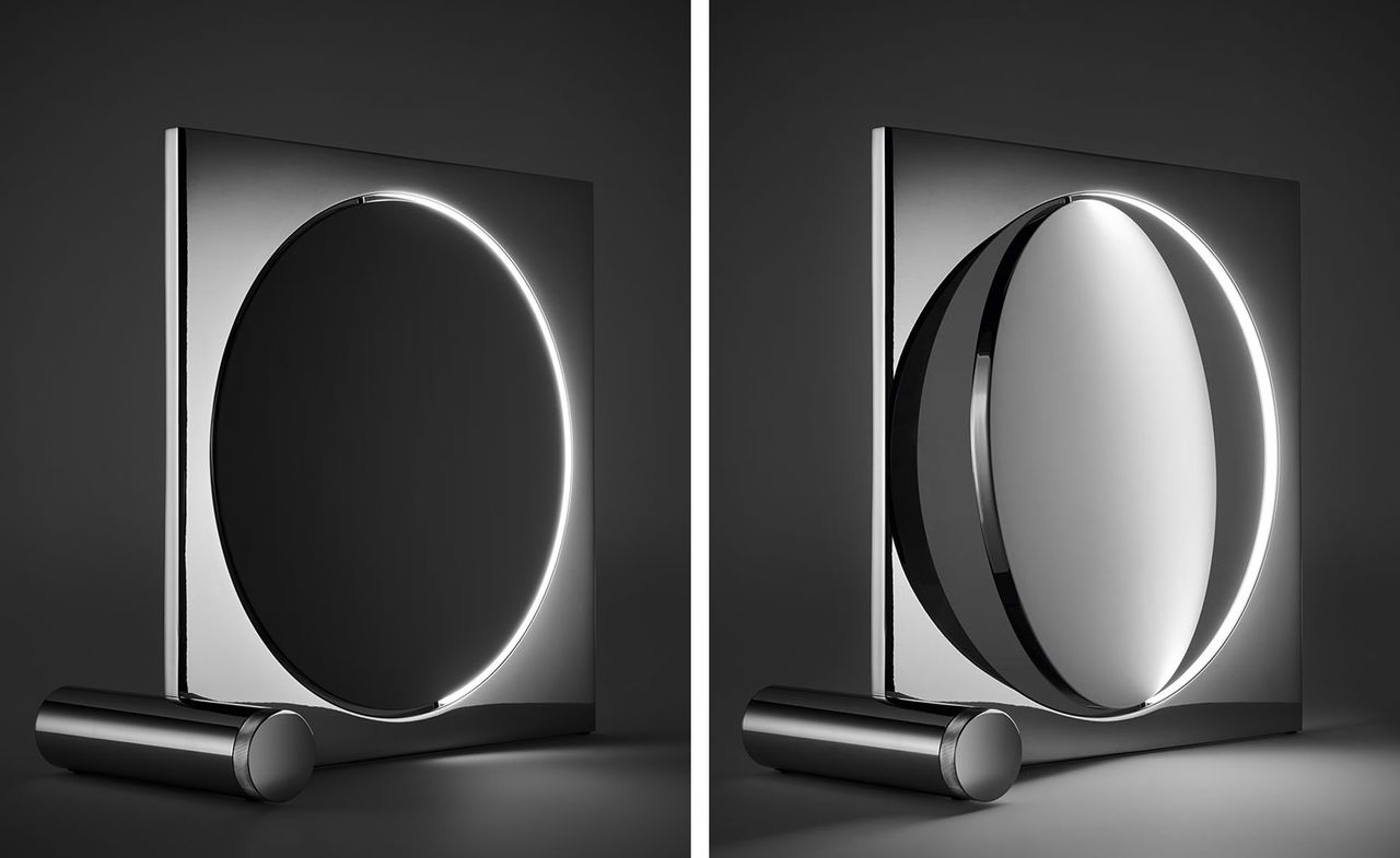 Two side-by-side photos of the chrome-plated &#039;Moonsetter&#039; floor lamp by Louis Poulsen. The photos show different views as the lamp&#039;s metal disc rotates mimicking the moon. It is pictured against a dark coloured background