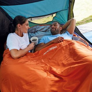 man and lady on sleeping bag with orange blanket