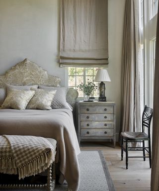 A grey bedroom idea with linen blinds, ornate headboard and wool blankets