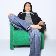Model wearing clothing with an exaggerated collar sold at Selfridges sat on a green armchair