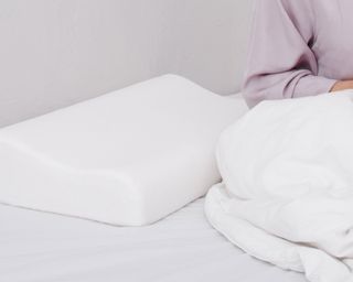 Lady on a bed with white sheets, duvet and memory foam pillow