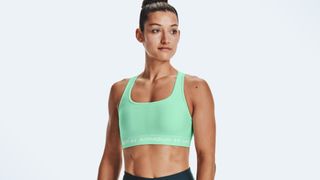 A photo of a woman wearing the Under Armour Mid Crossback Sports Bra, one of the best medium-impact sports bras