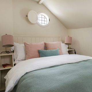 bedroom with cream wall and cushions on bed with lamp on table