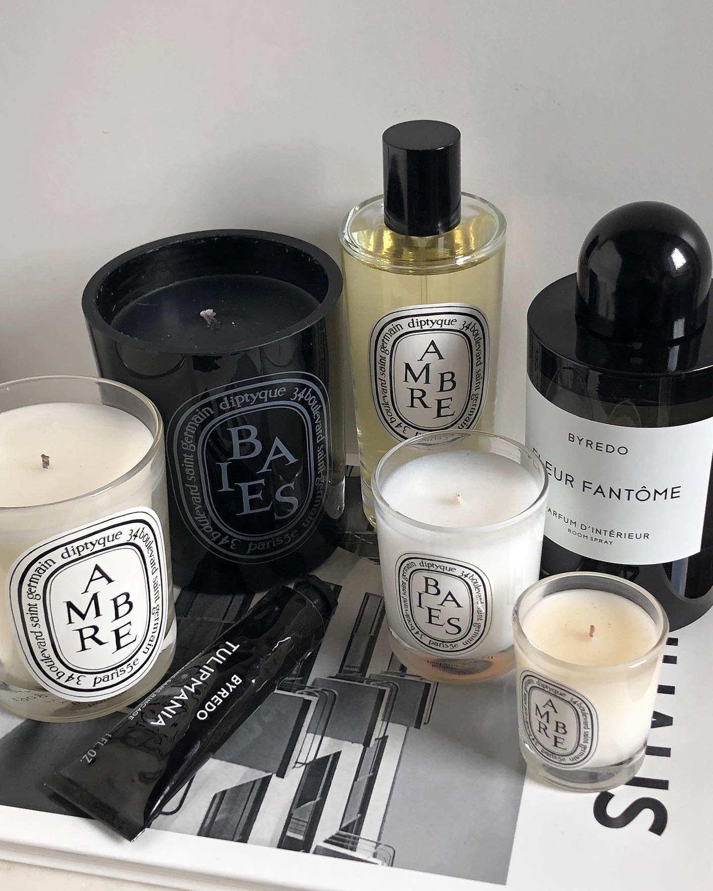 A coffee table book with Diptyque candles on top