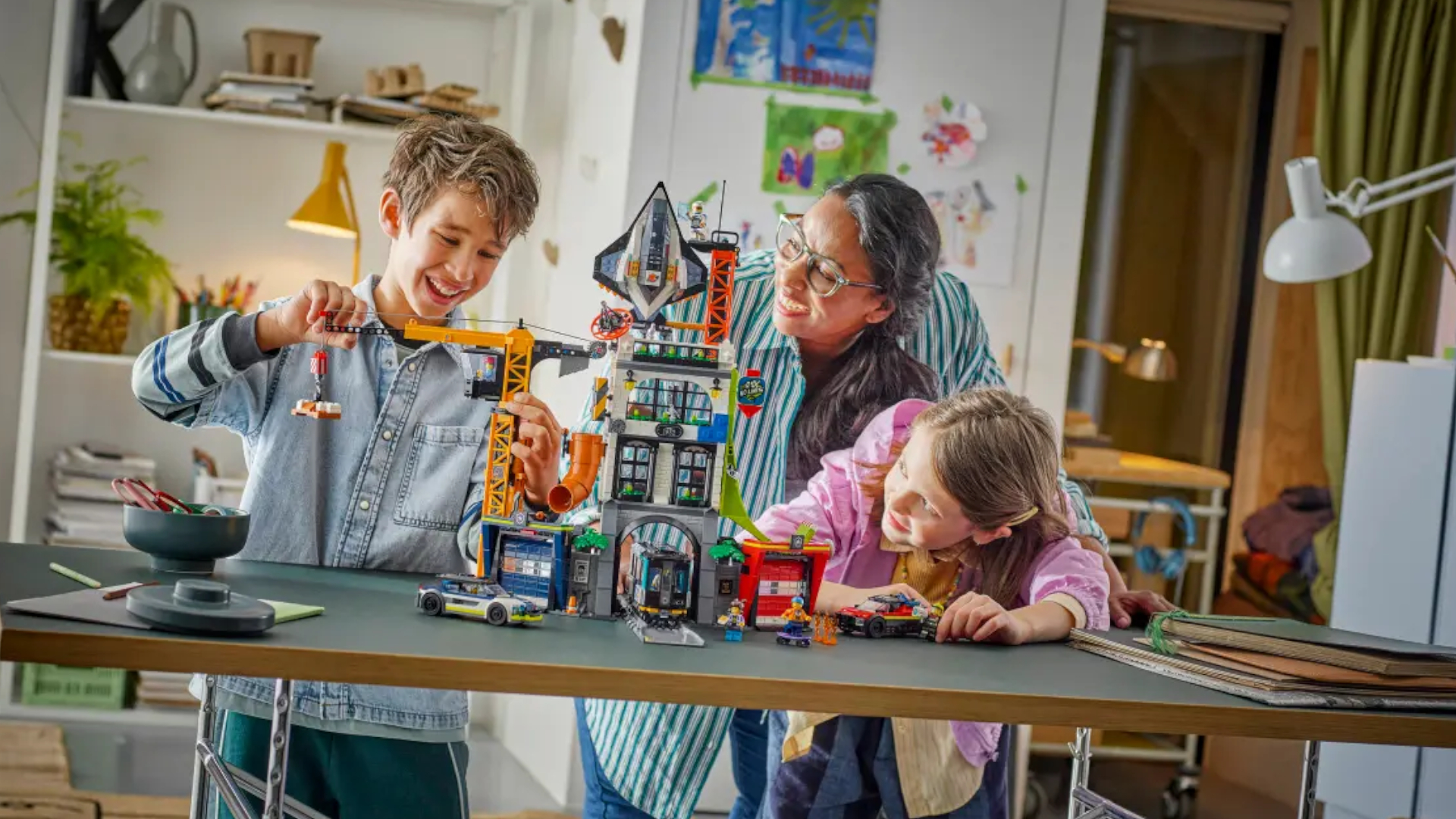 Lego The City Tower set being played with on a table by a smiling boy, girl, and woman