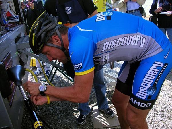 He Rides, he wrenches! Lance adjusts a new saddle. Check out Armstrong's one-off Giro Atmos Livestrong helmet