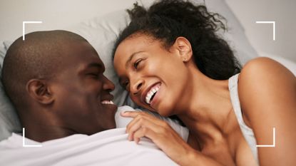 Couple laughing in bed together before trying out the pretzel sex position 