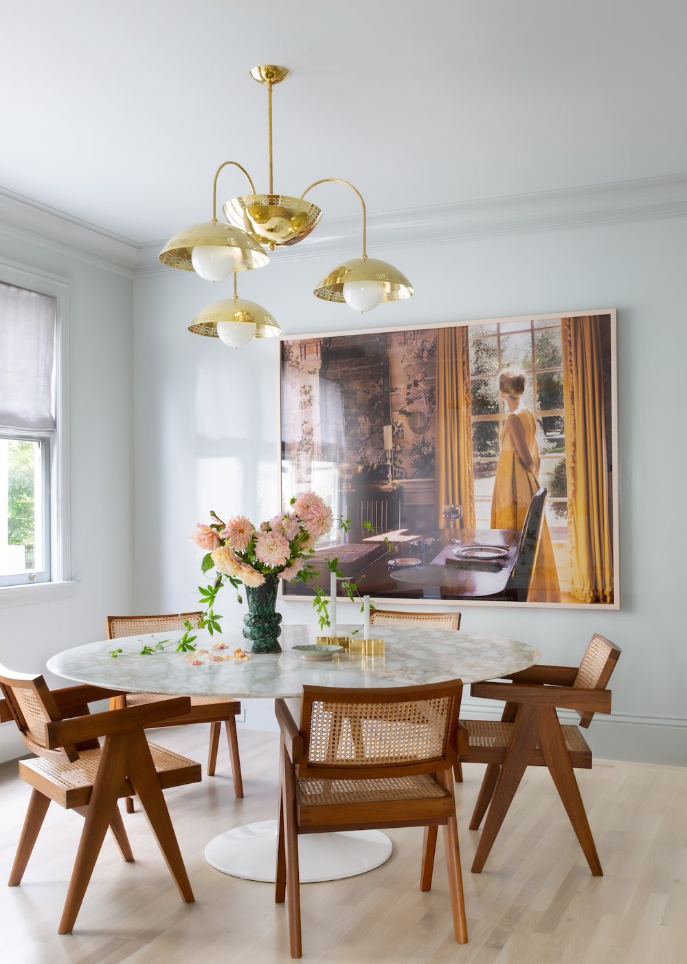 Dining room with cane chairs, gold light and statement artwork