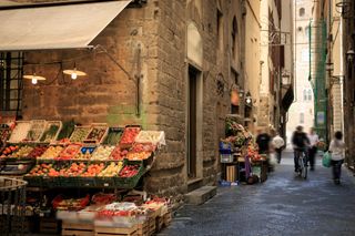 A narrow street in Florence, Italy, with a market stall.