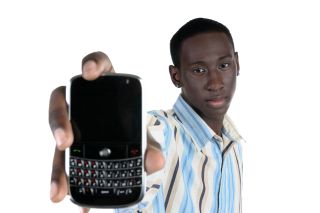 Teenage boy holds out his cell phone with keyboard. 