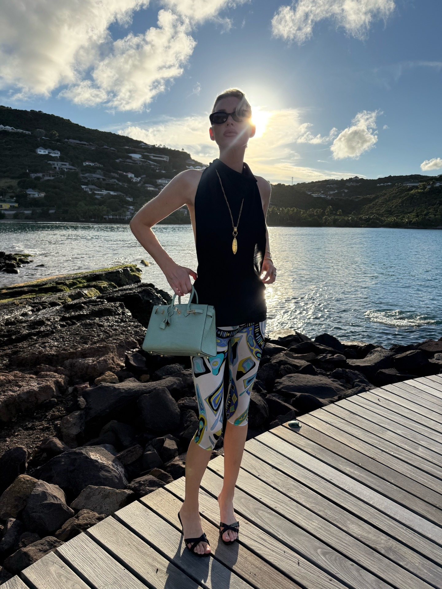 Elsa Hosk wearing a black halter top, printed capri leggings, and criss-cross sandals