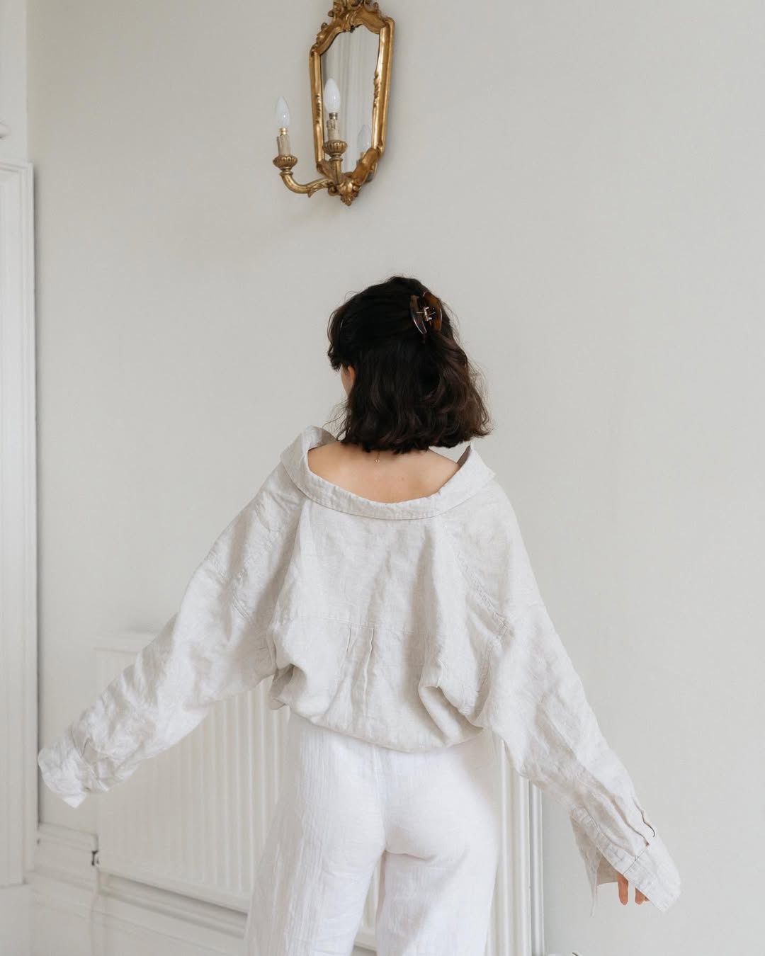 Woman wearing white with short hair and claw clip.