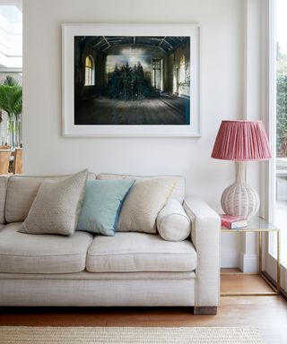 Grey walls, wooden floor ad grey sofa with framed picture above