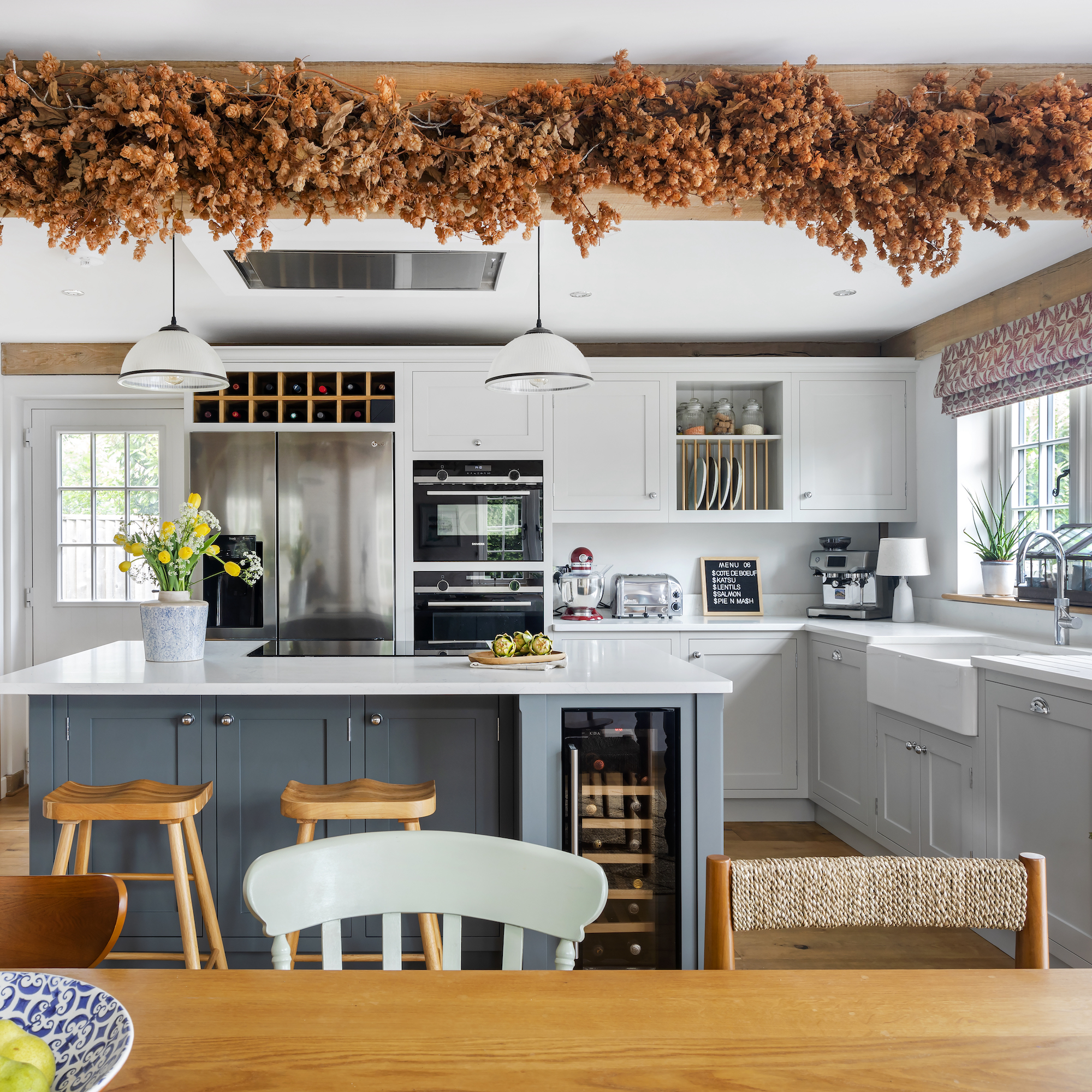 kitchen with blue island and beam decorated with dried hops