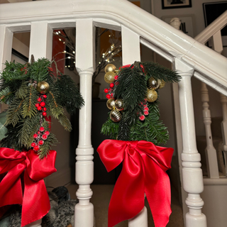 Two pool noodle spindles on a staircase with red ribbons.