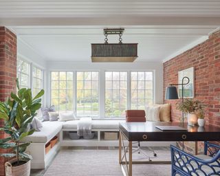 Light living area with exposed brick walls and white beadboard panels on ceiling