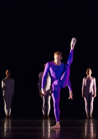 Male dancer doing a solo on stage in purple unitard