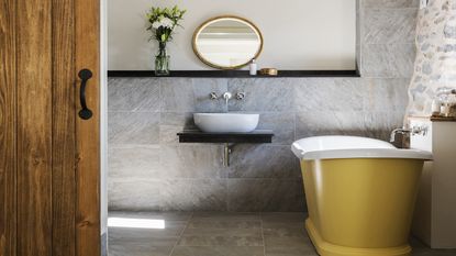 yellow boat bath in bathroom with natural stone walls