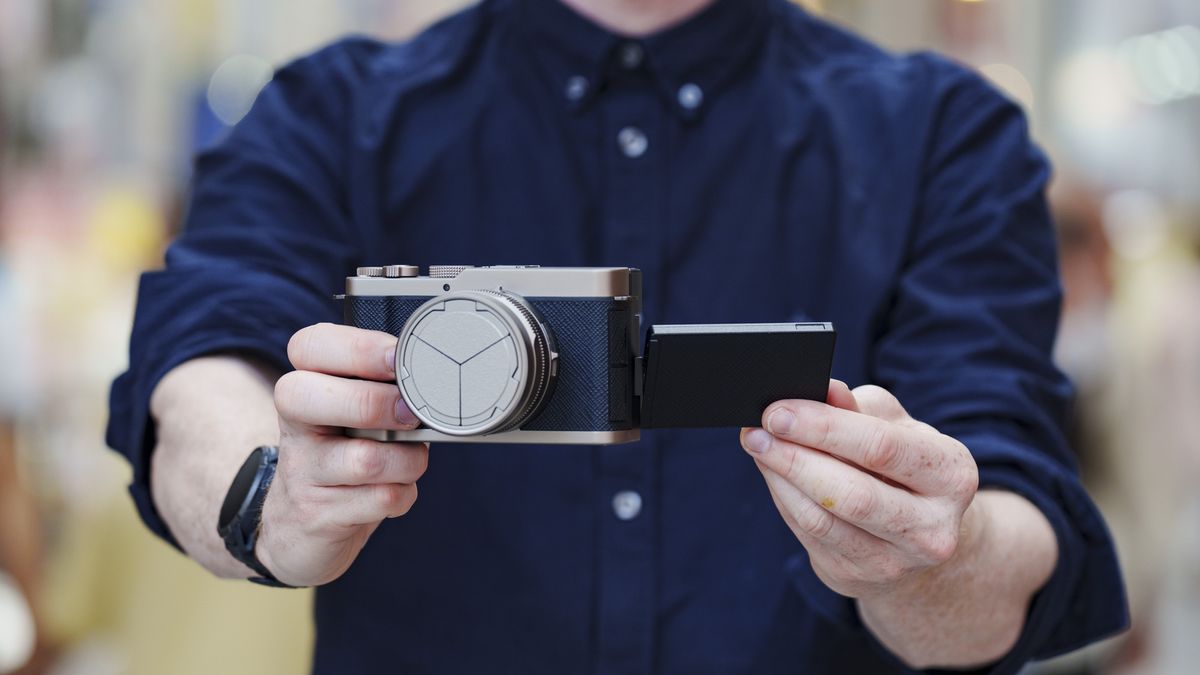 Man holding the Panasonic Lumix L10 compact camera in an urban setting of Japan