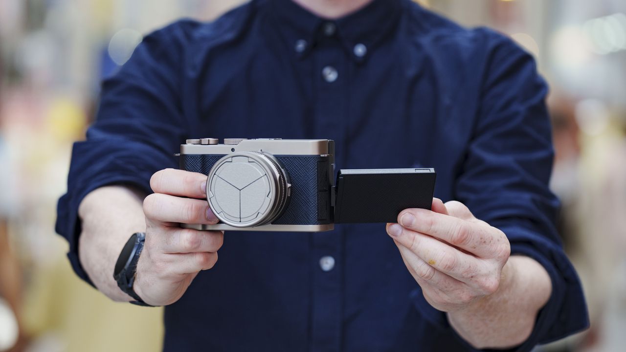 Man holding the Panasonic Lumix L10 compact camera in an urban setting of Japan