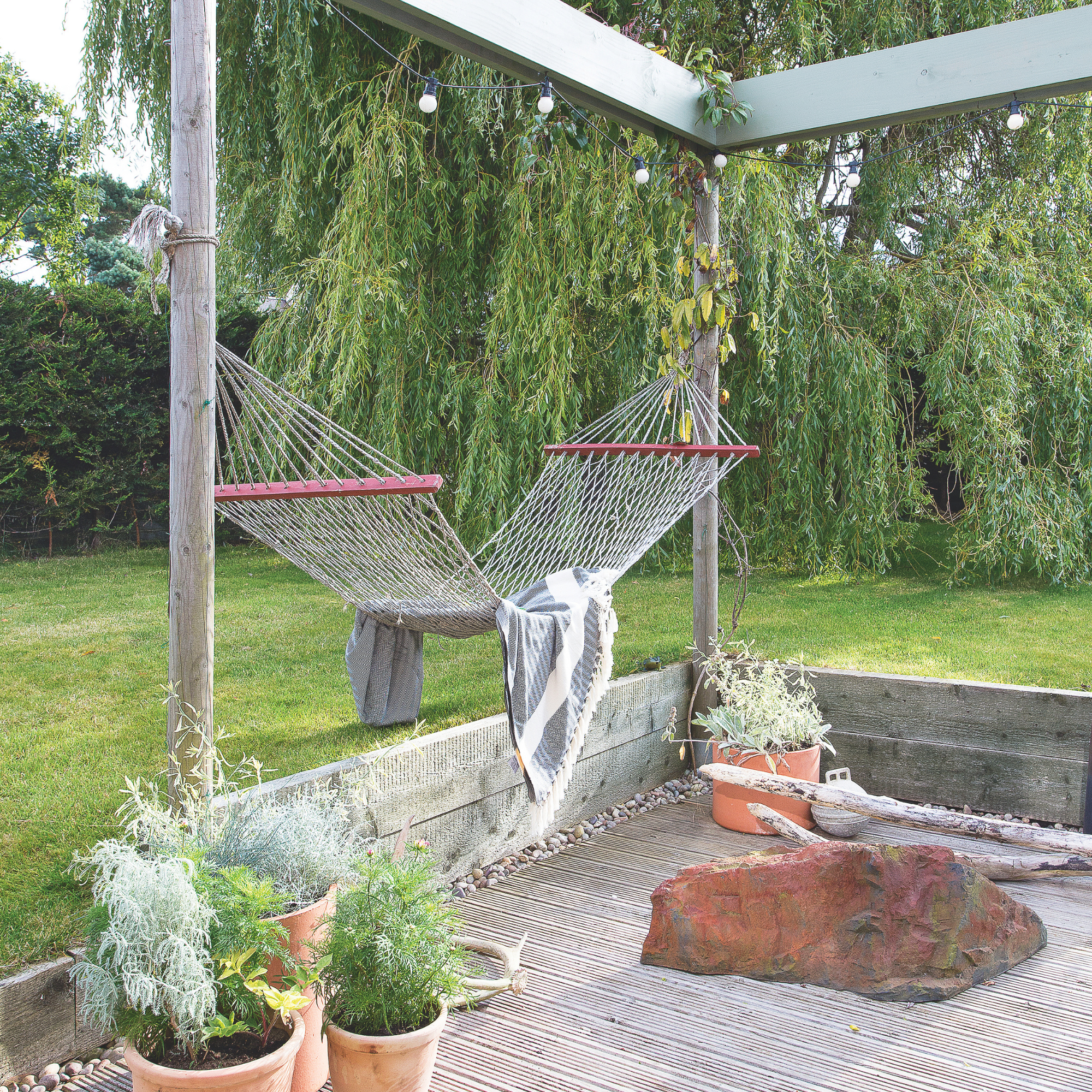Net hammock hanging from a pergola.