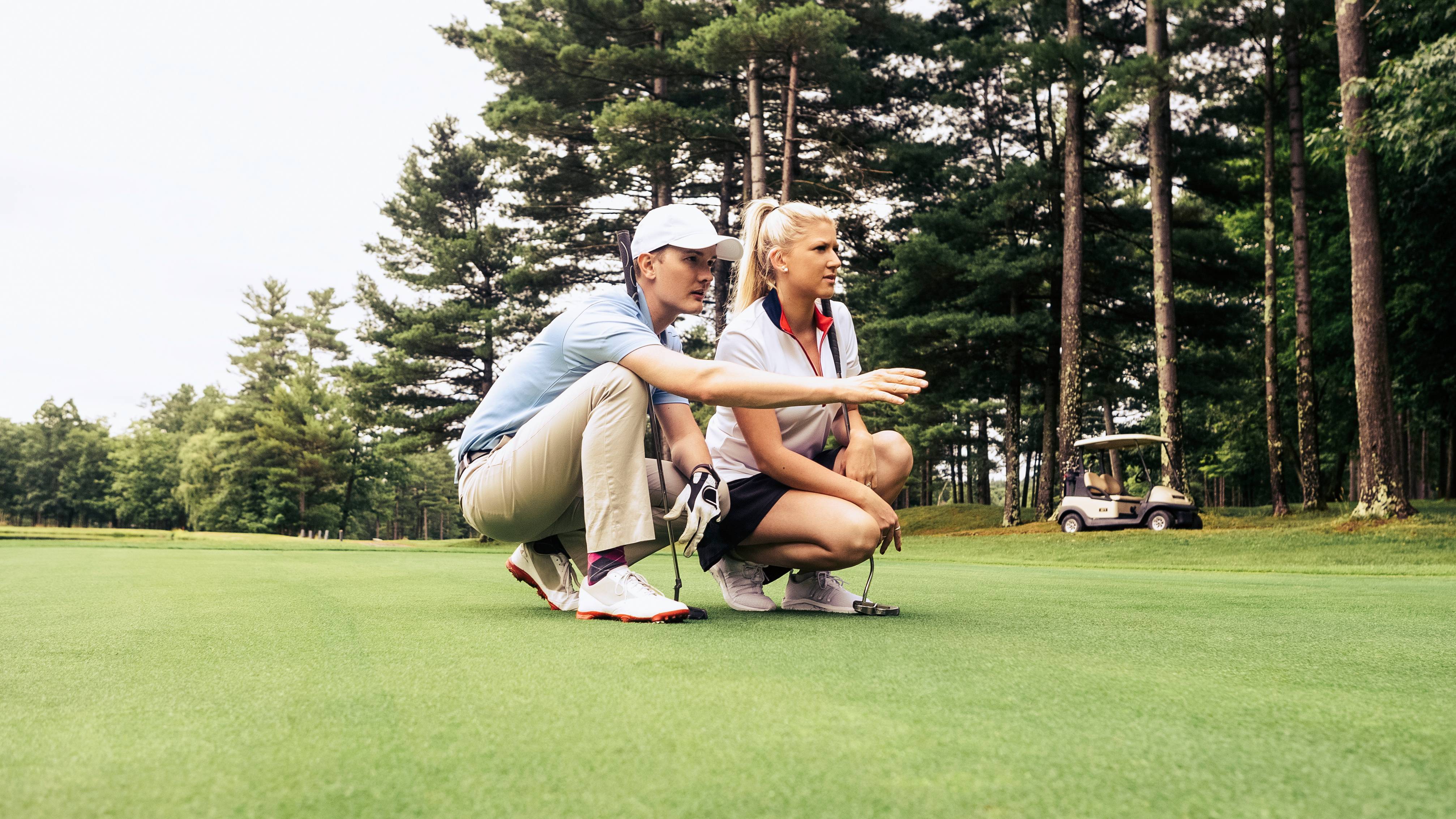 Male golfer helping female golfer to line up a putt