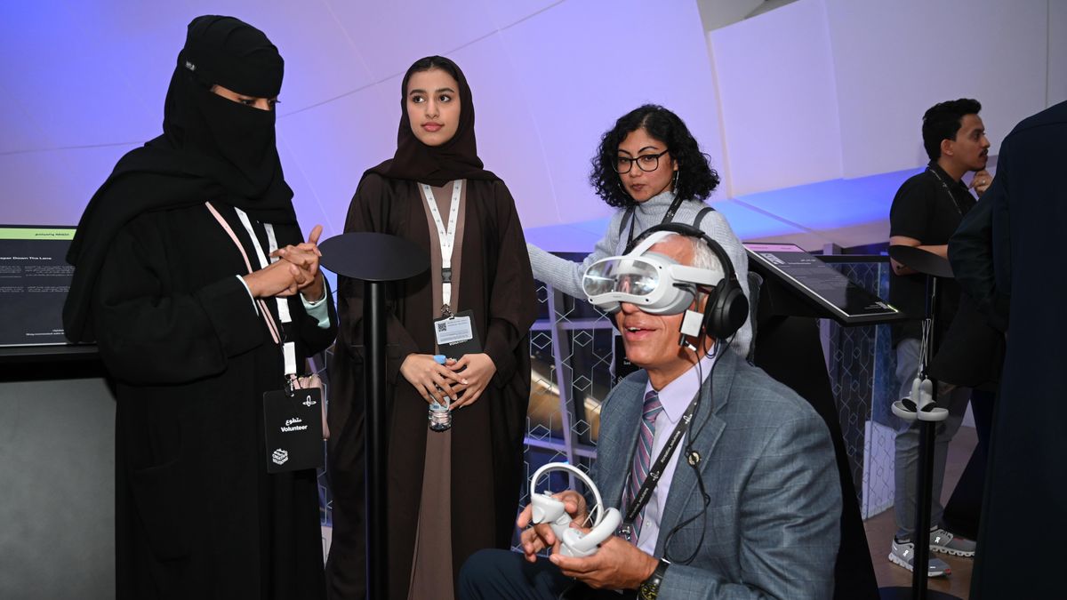 Three women watch a man use a virtual reality headset at a demo day