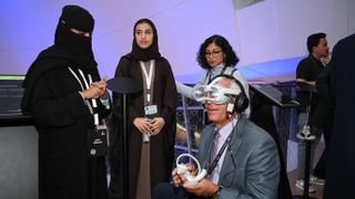Three women watch a man use a virtual reality headset at a demo day