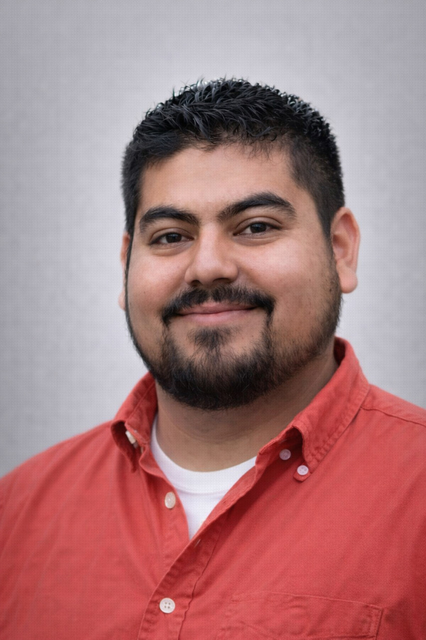 Headshot of man in orange shirt with dark hair