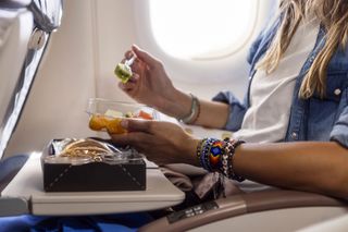 A woman eats food on a plane