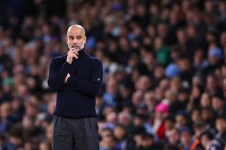 Pep Guardiola stands on the touchline with his hand on his chin, pondering