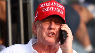 Donald Trump with phone wearing a red hat
