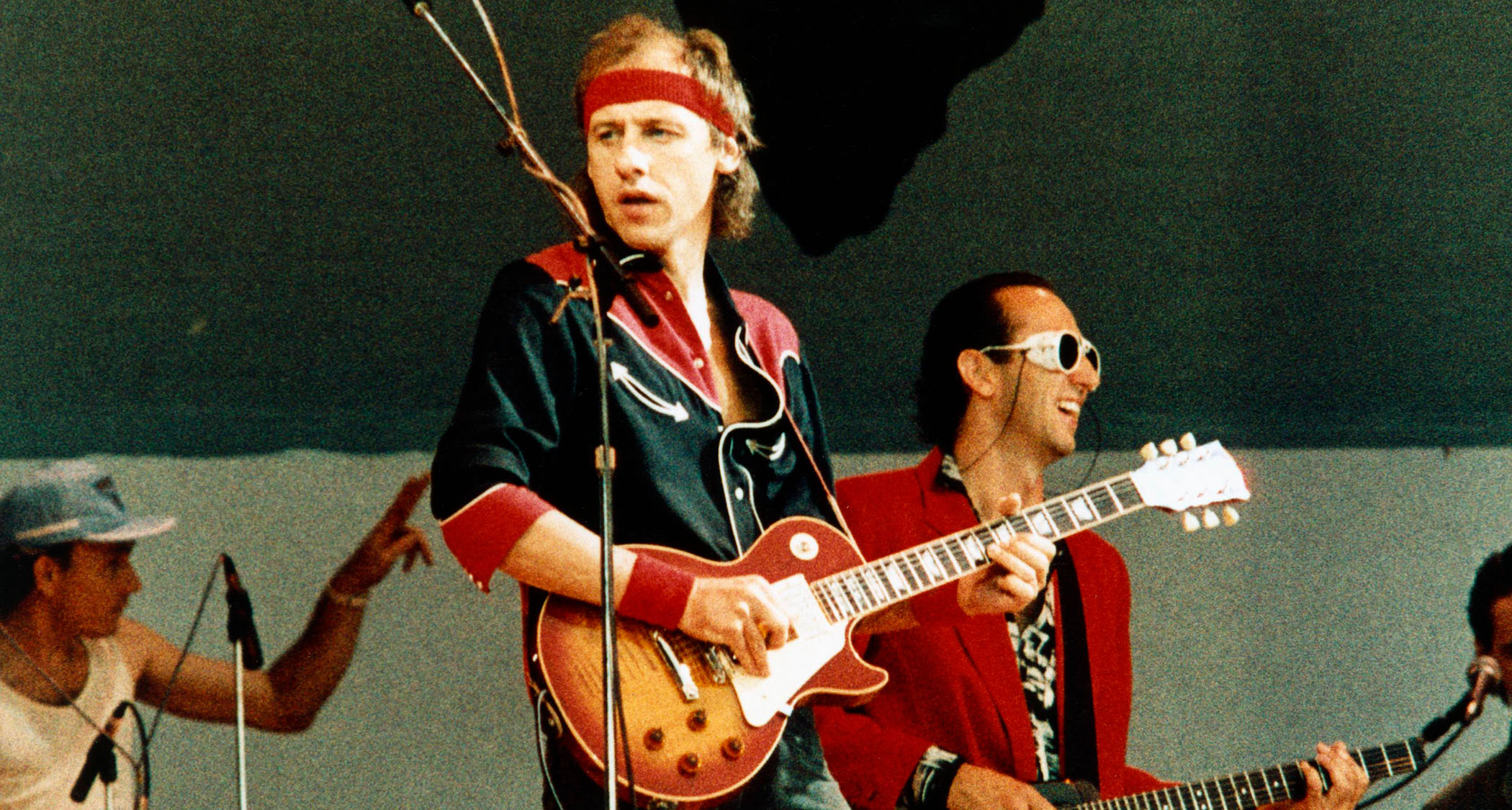 Mark Knopfler of Dire Straits performs at Live Aid in 1985. He plays a Gibson Les Paul Standard and wears his then-trademark red headband.