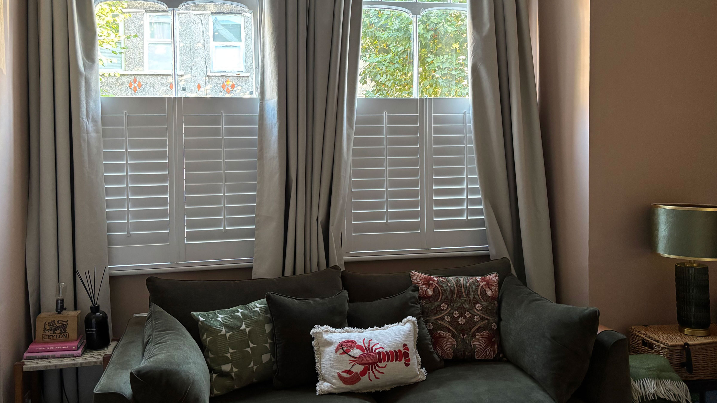 Floor length curtains behind a green sofa