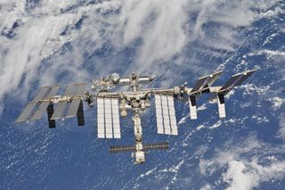 La station spatiale internationale peut être vue au premier plan avec le bleu et le blanc de la Terre derrière elle.