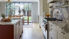 open plan kitchen diner with red kitchen island and marble worktops and splashbacks