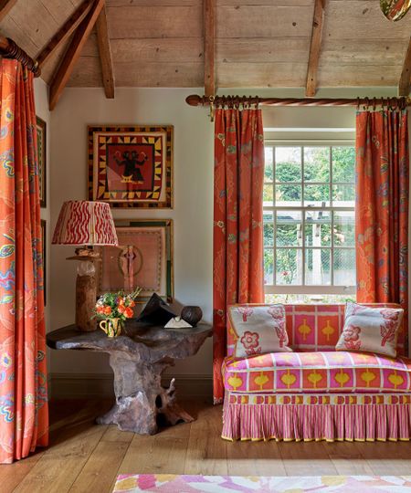 Living room by Kit Kemp with orange curtains and orange and pink sofa