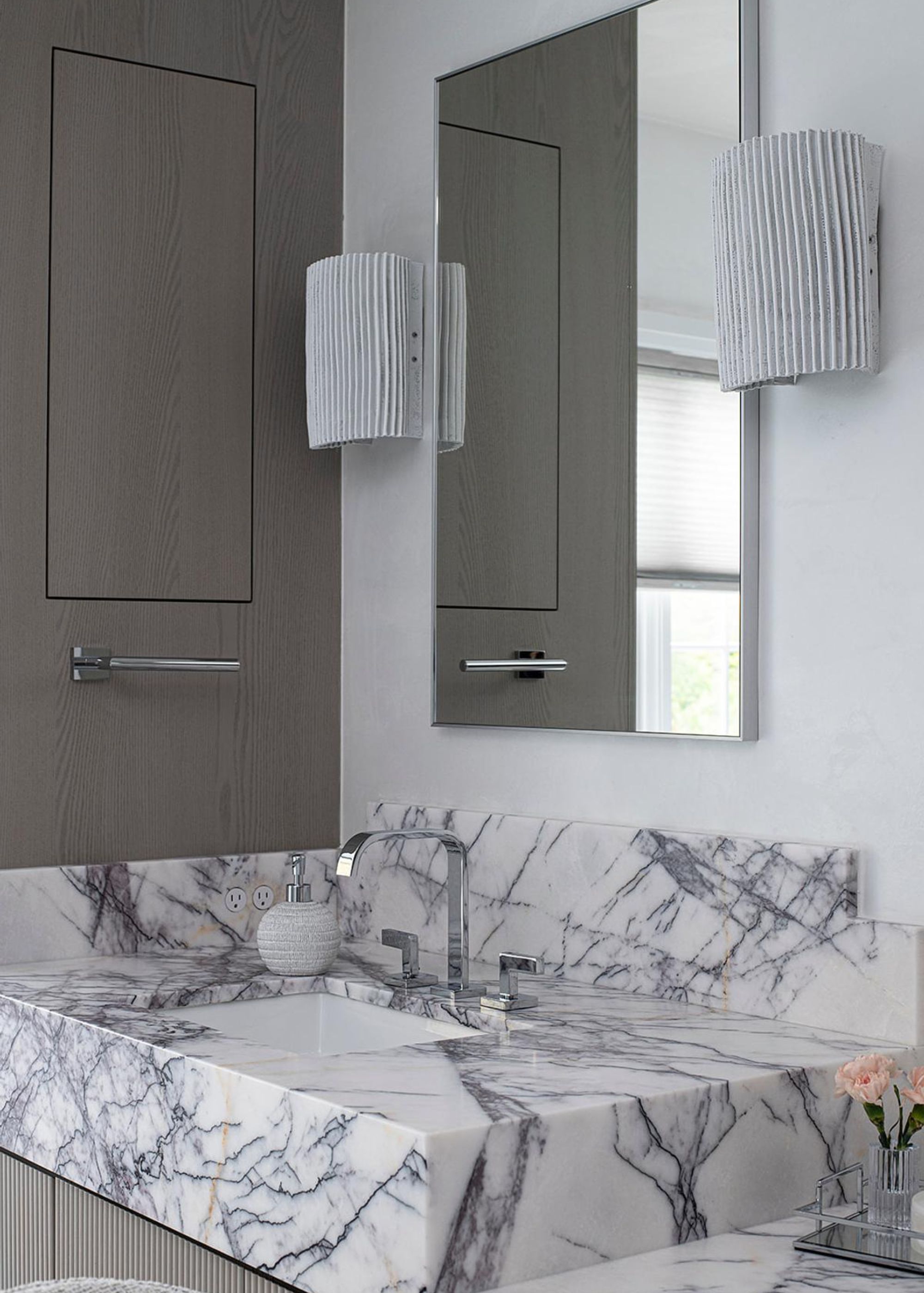 A quartzite bathroom countertop in a small bathroom. Above the sink is a mirror with lights on either side of it.
