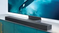 the Samsung HW-Q90R Soundbar on a cabinet beneath a TV