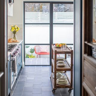 view through kitchen with wooden trolley island to crittal french doors