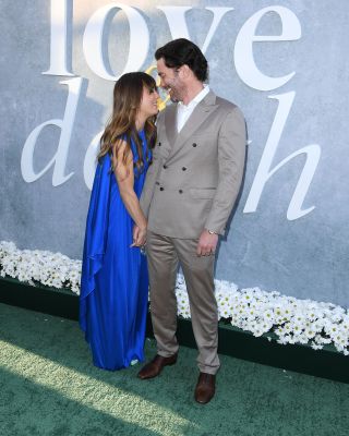 Kaley Cuoco and Tom Pelphrey holding hands and similing at each other at Love and Death premiere