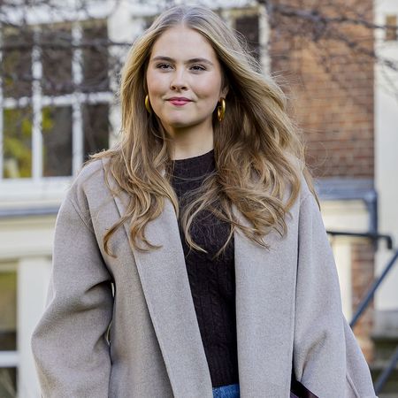 Princess Catharina-Amalia in a black top, wide leg jeans and and a gray overcoat at a photo call in November.