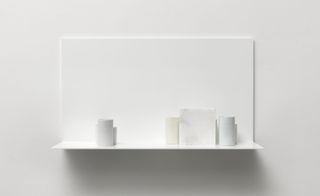 Seven porcelain vessels and one alabaster block in light gray, light yellow, and light blue are set on a white shelf.