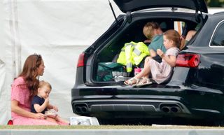 Kate Middleton with Prince George, Princess Charlotte, and Prince Louis at a polo match, eating a picnic from the back of a car